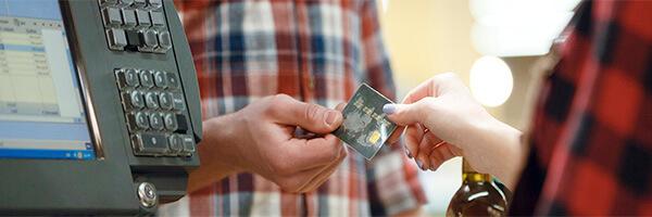 TPV Fijo - Hombre dando una tarjeta de credito a una cajera en un supermercado junto a un tpv